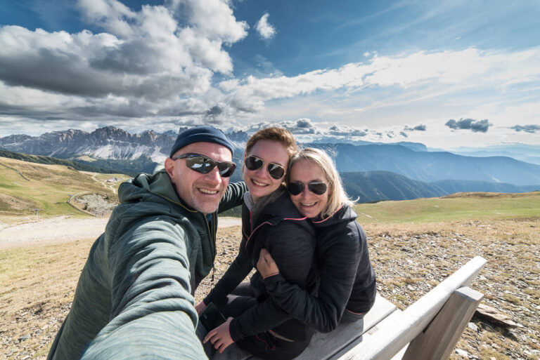 Die Gastgeber auf einer Bank, im Hintergrund die Berge